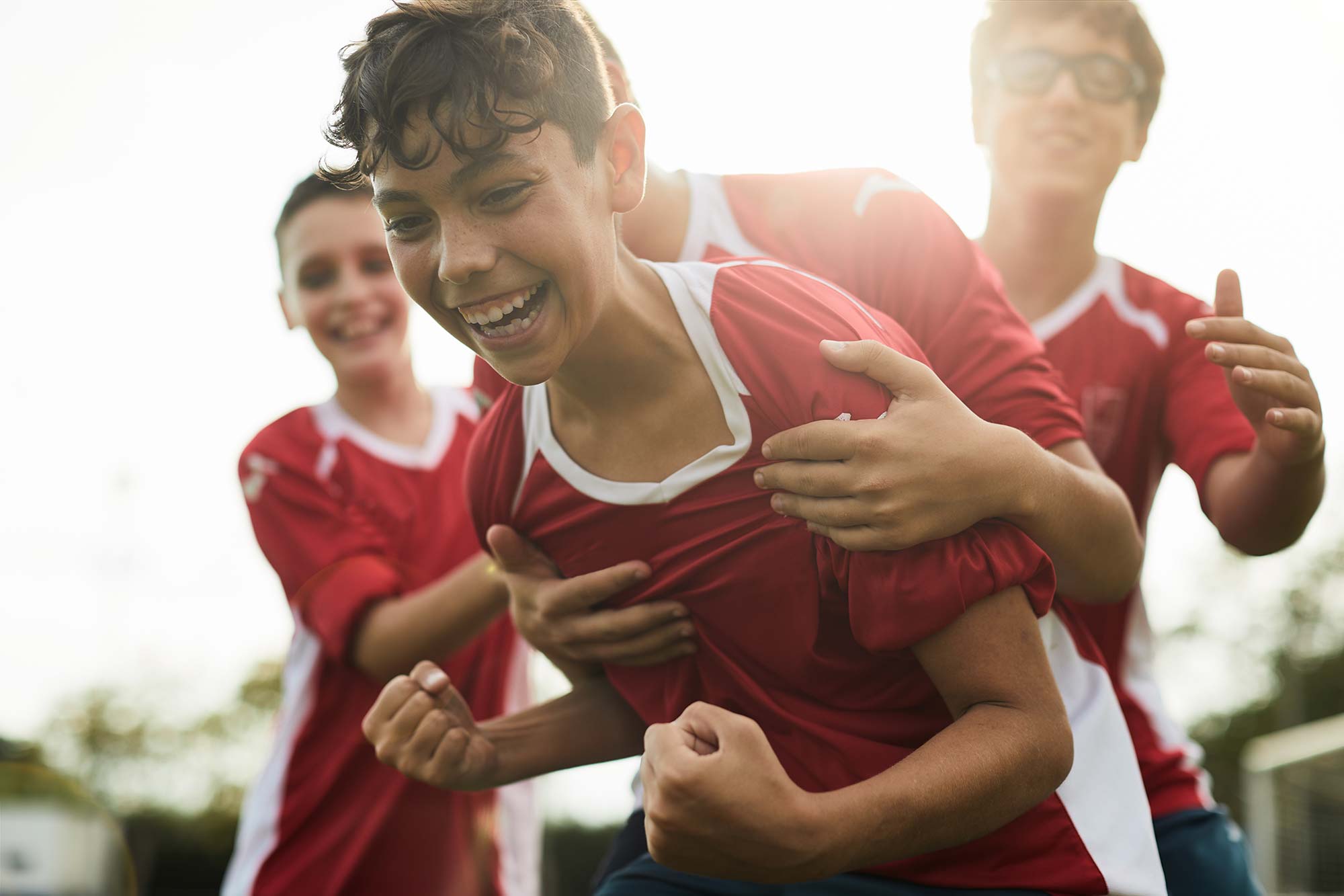 Young kids celebrate a goal on a football field, jumping with excitement and joy after scoring, capturing the thrill of the game