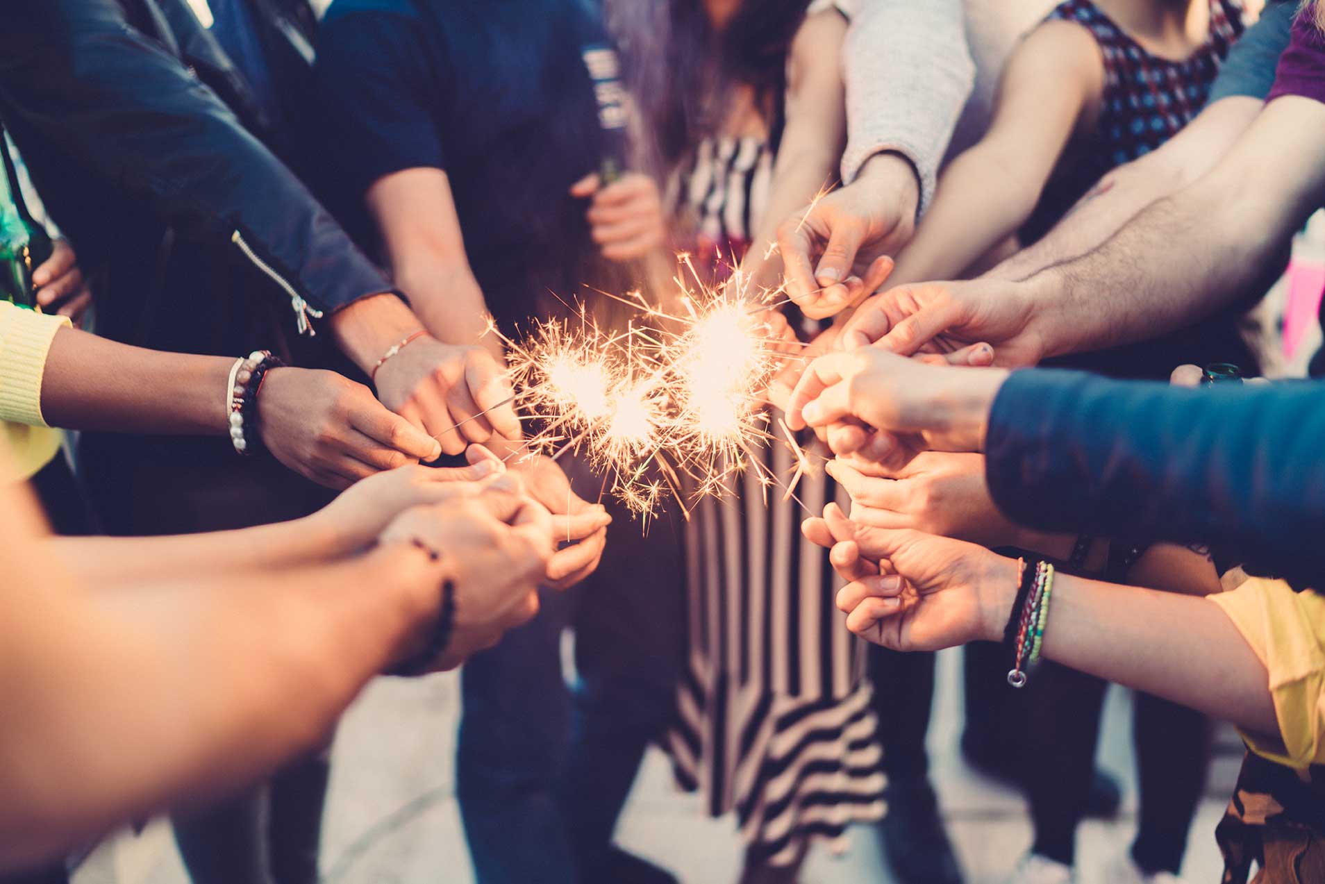 Group of people in the circle holding sprinkles in the middle